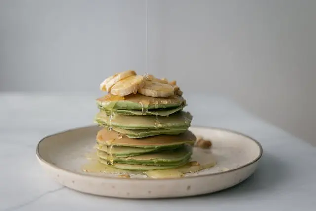 Appetizing pancakes with fresh banana poured with honey . Healthy low-sugar, gluten-free dessert arranged beautifully on a table